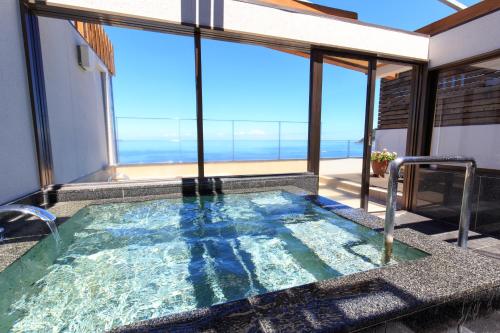 a hot tub with a view of the ocean at Kameya Rakan in Ito