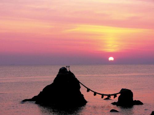 鳥羽市にある扇芳閣の岩の上のロープを持つ海岸の夕日
