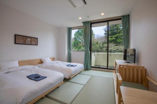 a bedroom with two beds and a tv and a window at Hakone Kowakien Miyamafurin in Hakone