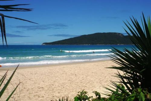 a beach with people surfing in the ocean at Apto Praia Ingleses 3q 2g in Florianópolis