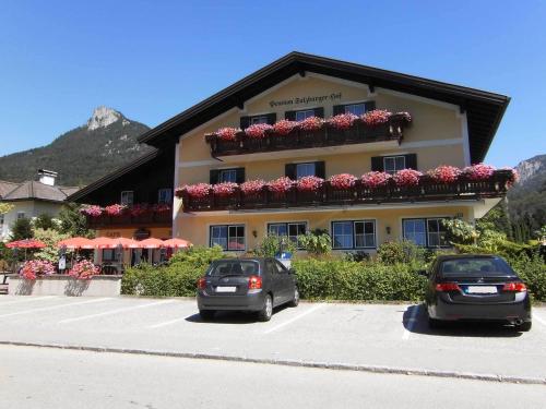 two cars parked in a parking lot in front of a building at Pension Salzburger Hof in Fuschl am See