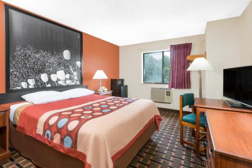 a hotel room with a bed and a desk and a television at Super 8 by Wyndham Kent/Akron Area in Kent