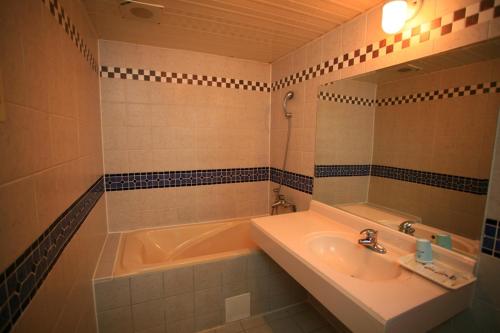 a bathroom with a tub and a sink and a mirror at Paiwei Motel in Tainan