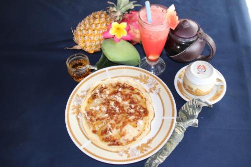 a table with a plate of food and a pineapple and a drink at Blue Star Bungalows & Cafe in Amed
