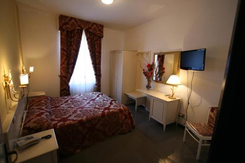 a bedroom with a bed and a window and a television at Hotel La Meridiana in Anghiari