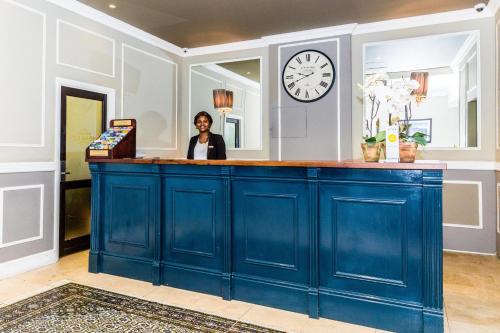 a woman is standing behind a blue counter at Innscape Classic Hotel in Cape Town