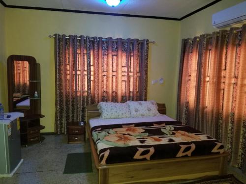 a bedroom with a bed in a room with windows at Nass Lodge in Sunyani