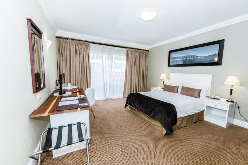 ein Hotelzimmer mit einem großen Bett und einem Schreibtisch in der Unterkunft Innscape Classic Formely The New Tulbagh Hotel in Kapstadt