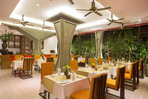 a restaurant with white tables and chairs and plants at Golden Temple Villa in Siem Reap