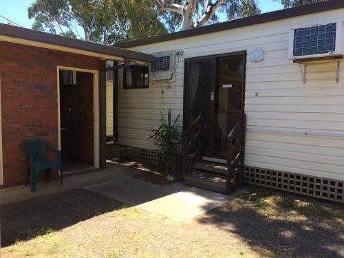 a porch of a house with a door and a chair at Golden Country Motel and Caravan Park in Maryborough