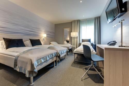 a hotel room with two beds and a desk and a television at Tyrifjord Hotell in Vikersund