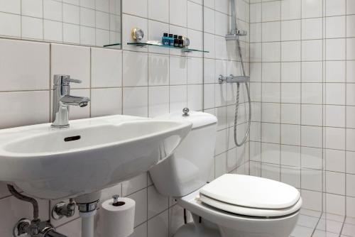 a white bathroom with a sink and a toilet at Tyrifjord Hotell in Vikersund