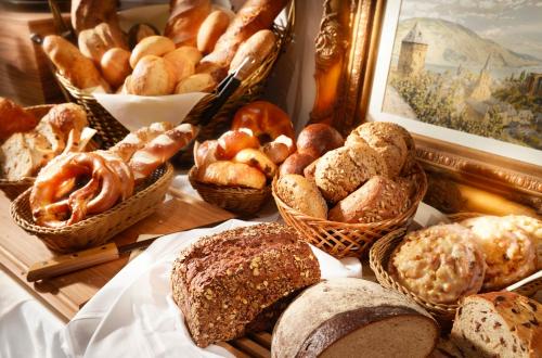 a table topped with baskets of bread and pastries at Hotel am Markt Bacharach in Bacharach