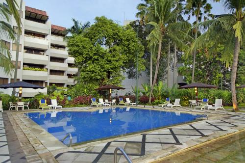 a swimming pool with chairs and umbrellas next to a building at Hotel Borobudur Jakarta in Jakarta