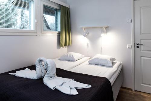 two beds in a hotel room with towels on the bed at Holiday Linnunlahti in Joensuu