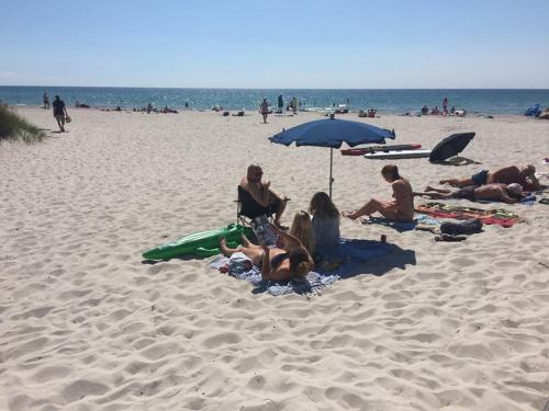 a group of people sitting on the beach under an umbrella at Casablanca Hostel, hyggelig overnatning in Anholt