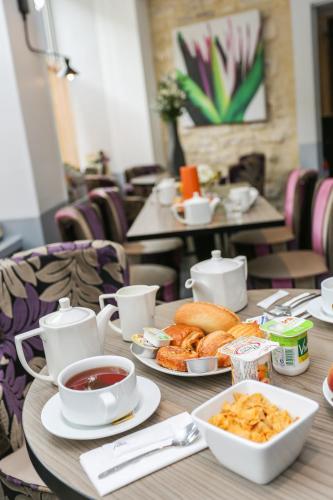 einen Holztisch mit Teller mit Speisen und Kaffee darauf in der Unterkunft Appart Hotel Avalon in Paris