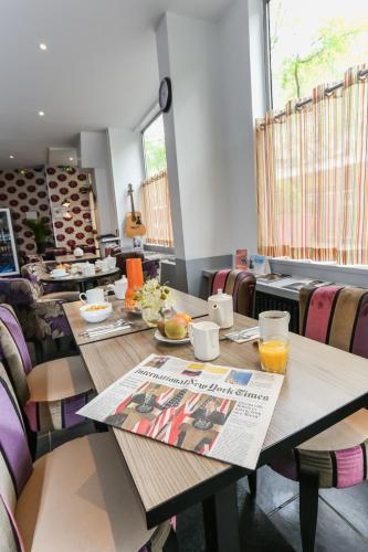 - une salle à manger avec une table et un journal dans l'établissement Résidence Avalon, à Paris