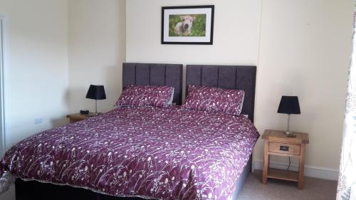 a bedroom with a bed with a purple comforter at Kilsham Farm in Petworth