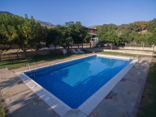 una piscina de agua azul en un patio en Las Cabañas de La Vera en Aldeanueva de la Vera