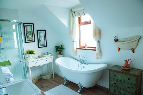 ein blaues Badezimmer mit einer Badewanne, einem Waschbecken und einer Badewanne in der Unterkunft Cherrytree House B&B in Moville