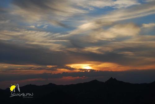 a person standing on top of a mountain at sunset at SunAlpin - Ferienwohnungen in Schoppernau