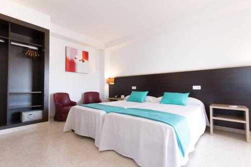 a bedroom with a large bed with blue pillows at Hotel Orosol by Typic Hotels in San Antonio