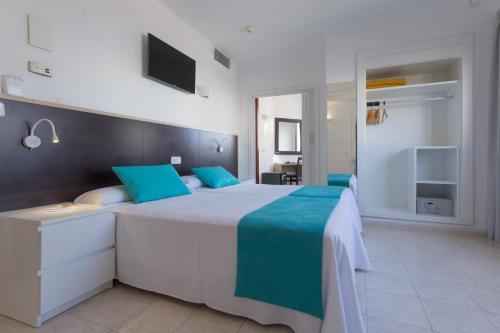 a bedroom with a large white bed with blue pillows at Hotel Orosol by Typic Hotels in San Antonio