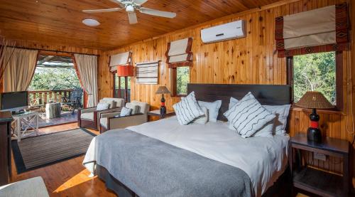 1 dormitorio con 1 cama y sala de estar en Kariega Game Reserve Main Lodge, en Kenton on Sea