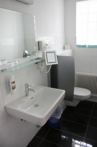a white bathroom with a sink and a toilet at Turmhof Breitenbrunn in Breitenbrunn