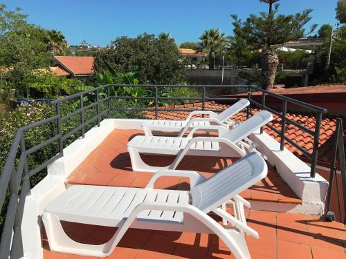 a row of white lounge chairs on a roof at Hotel Village Eden in Capo Vaticano