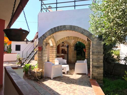 a patio with white chairs and an archway at Hotel Village Eden in Capo Vaticano