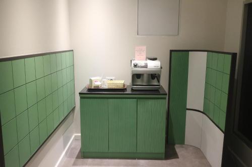 a room with green tiled walls and a counter with a microwave at Floral Shire Suvarnabhumi Airport in Lat Krabang