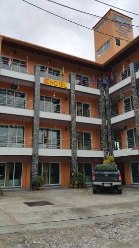 an orange hotel with a truck parked in front of it at B and B Hotel in Ranong