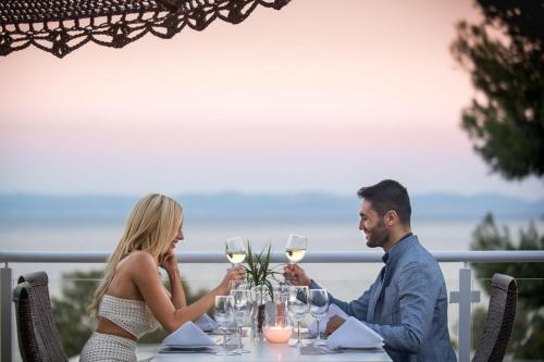 a man and woman sitting at a table with wine glasses at Kappa Resort in Paliouri
