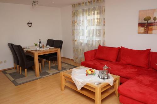 ein Wohnzimmer mit einem roten Sofa und einem Tisch in der Unterkunft Ferienwohnung Jungbauernhof in Alpirsbach