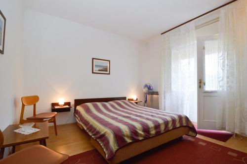een slaapkamer met een bed, een stoel en een raam bij Apartment Nela 23 in Pula