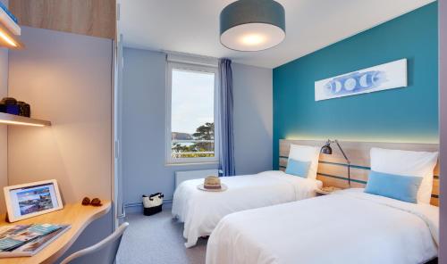 a hotel room with two beds and a desk and a window at Village Vacances de Pen-Hir in Camaret-sur-Mer