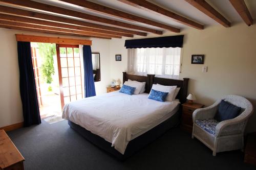 a bedroom with a large bed and a chair at Acara Guest Cottages in Stellenbosch