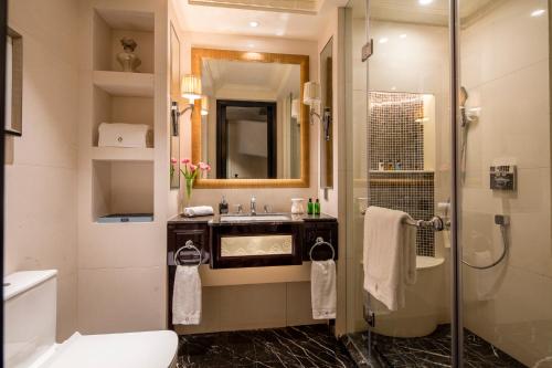 een badkamer met een douche, een wastafel en een toilet bij The Pury Hotel in Yiwu