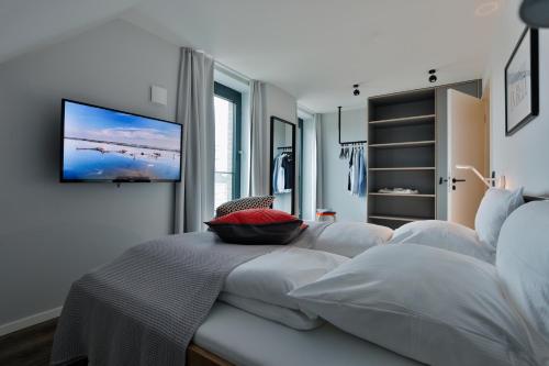 una camera da letto con un letto e una TV a parete di Bett&Bude Boardinghouse a Westerland