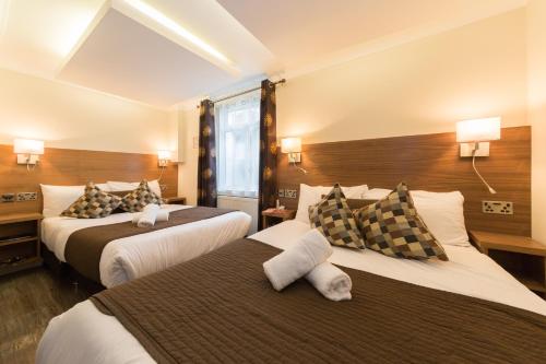 a hotel room with two beds and two lamps at Chester Hotel in London