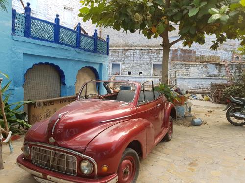 an old red car parked in front of a building at Yogis Guest House in Jodhpur