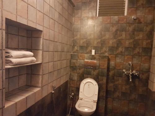 a tiled bathroom with a toilet and towels at Yogis Guest House in Jodhpur