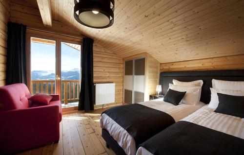 une chambre avec deux lits et une chaise et une fenêtre dans l'établissement Odalys Chalet Mont Soleil, à Mâcot La Plagne