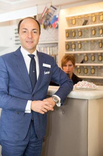 a man in a suit standing next to a counter with a cake at Hotel Helvetia in Genova