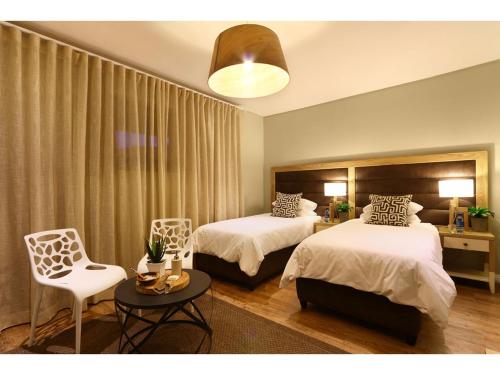 a bedroom with two beds and a table and a chair at Aquila Private Game Reserve & Spa in Touwsrivier