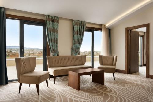 a living room with two chairs and a table and windows at Ramada by Wyndham Yalova in Yalova