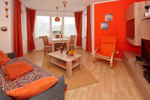 バンシンにあるBlaue Welle Whg_ 10のオレンジ色の壁のリビングルーム(テーブル、ソファ付)