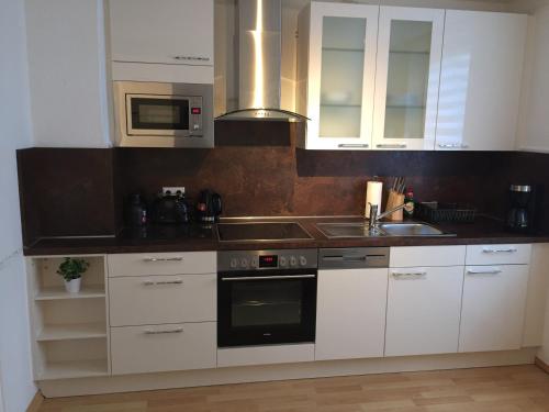 a kitchen with white cabinets and a sink and a microwave at Big and Beautiful in Hannover